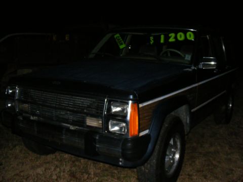 Dark blue Jeep Cherokee Wagoneer with wood paneling. Price tag in window says $1200