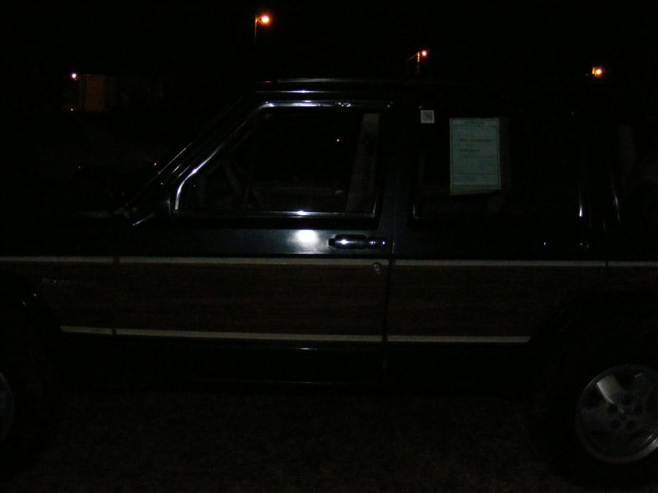 Dark SUV with wood paneling and a sticker on the rear passenger window