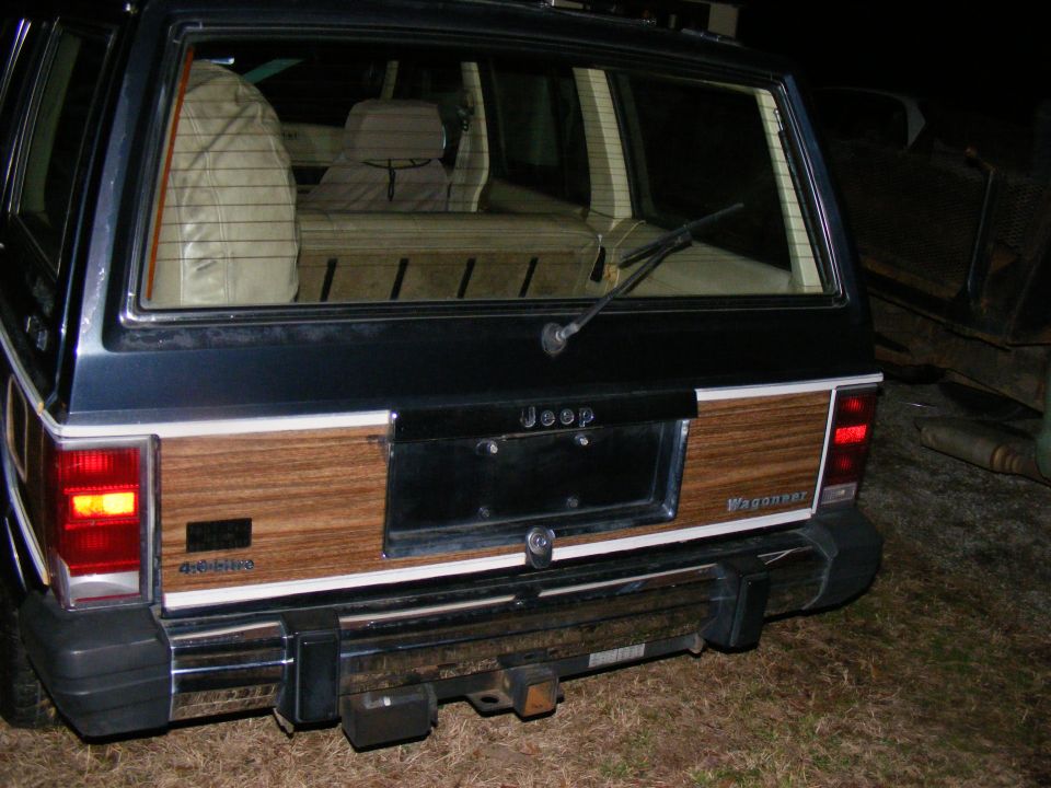 Rear view of a Jeep Grand Wagoneer with wood paneling and a trailer hitch