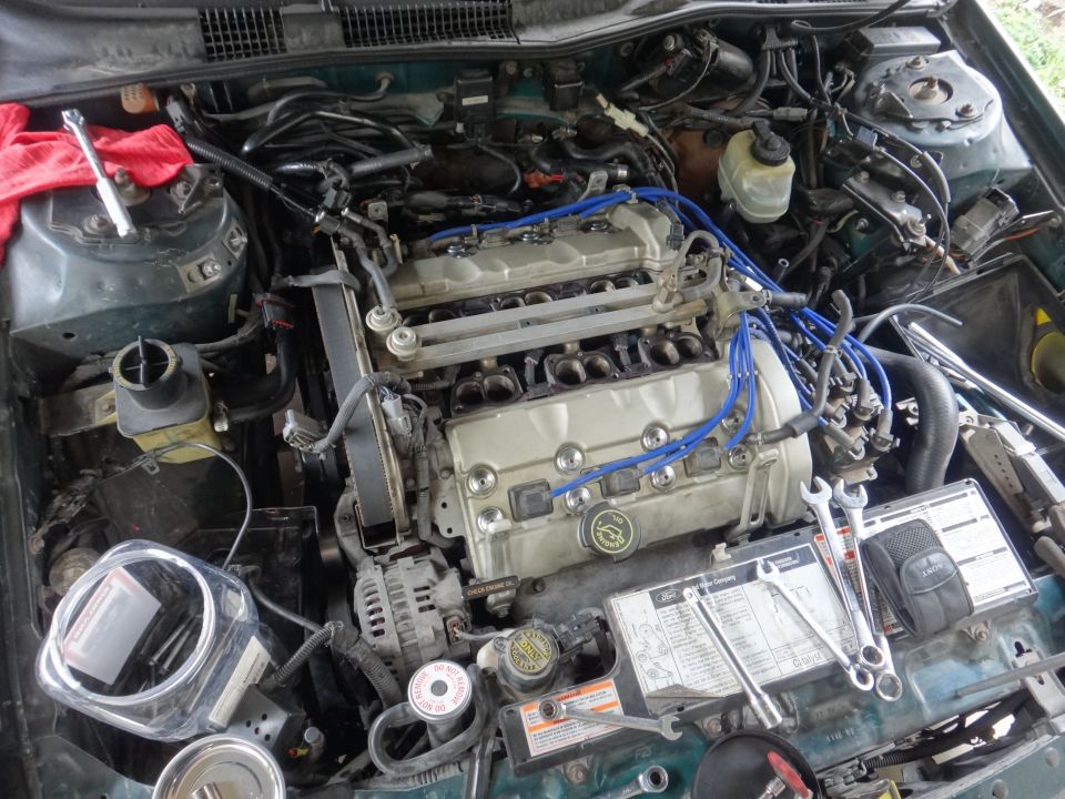Ford engine bay with tools and a red rag. A Ford logo is visible on the engine cover
