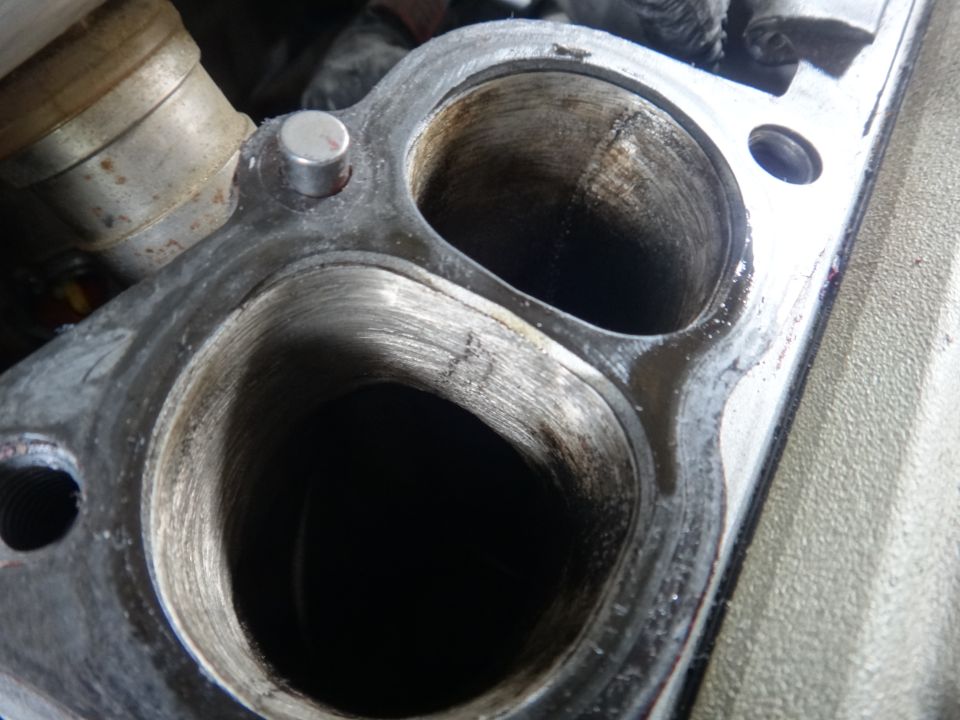Close-up of an engine intake manifold with two ports showing wear and carbon buildup