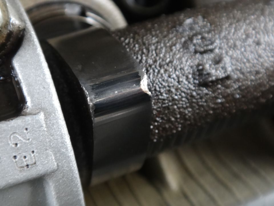 Close-up of a damaged metal engine component, possibly a camshaft or crankshaft bearing surface