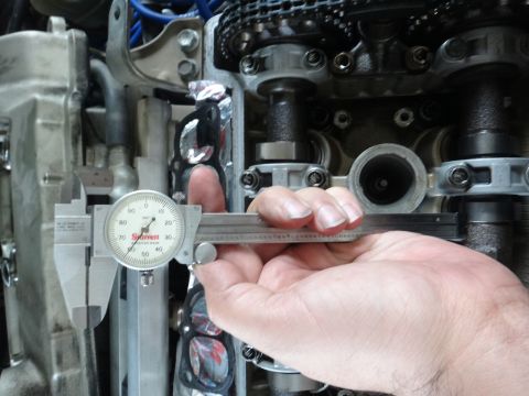 1993 Ford Taurus - A caliper is used to measure components within an engine's valve train, suggesting a diagnostic or repair procedure.