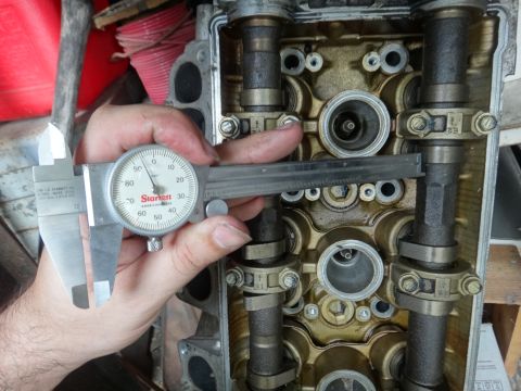 1993 Ford Taurus - Measuring engine valve stem clearance with a dial caliper on a cylinder head.