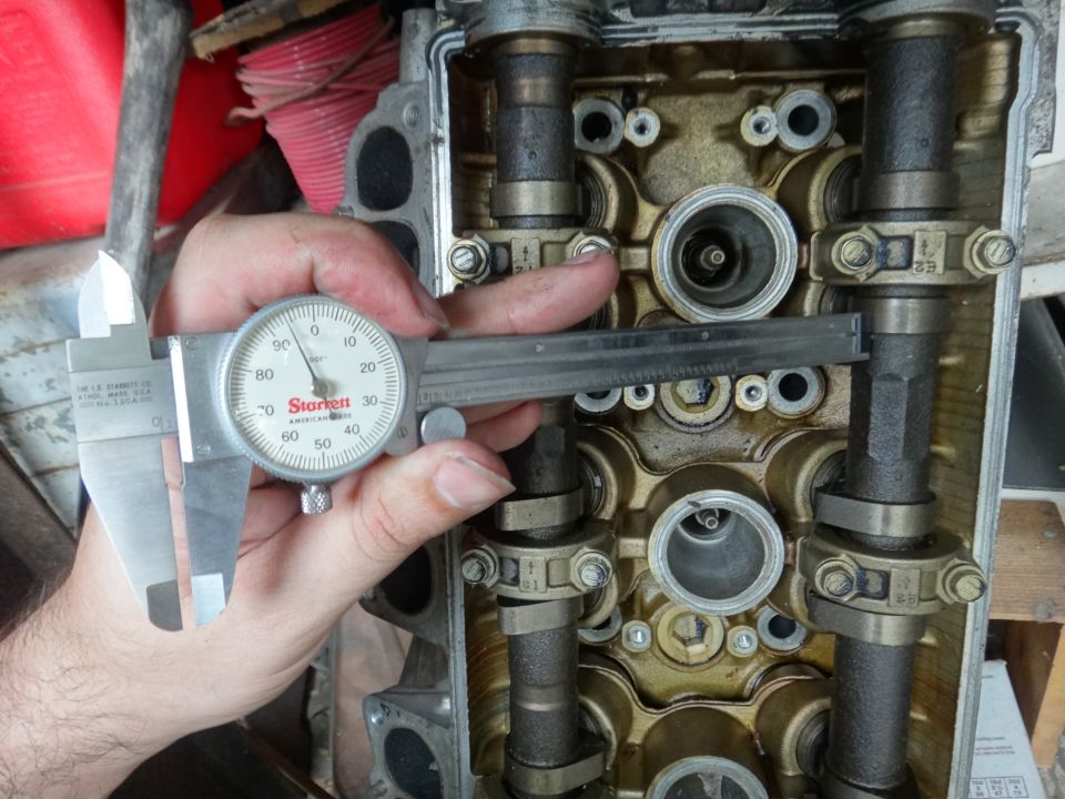 Dial caliper measuring engine valve stem on cylinder head