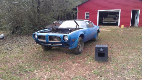 1970 Pontiac Trans Am - A blue 1970 Pontiac Trans Am is parked outside a red barn with its hood up, while another vehicle is visible inside the garage.