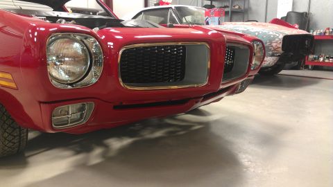 1972 Pontiac Trans Am - Front view of a red 1970s muscle car, possibly a Firebird, with its hood open, parked next to another vehicle.