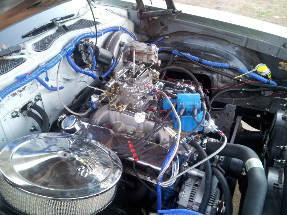 Engine bay with chrome air cleaner, carburetor, and blue wiring loom