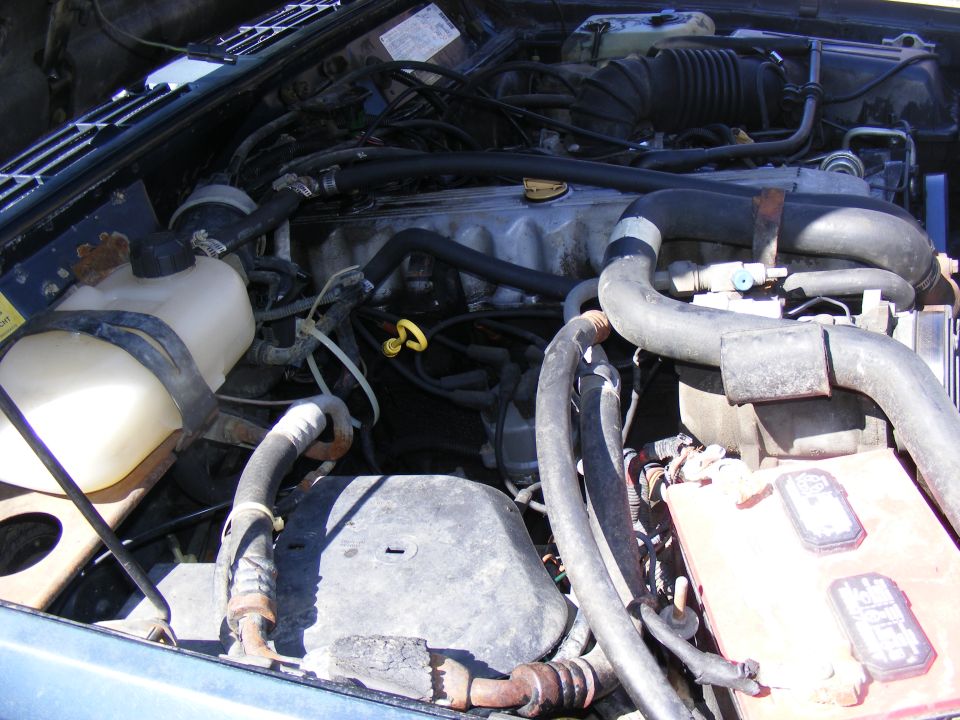 Jeep engine bay with hoses and engine block visible. Some text on a yellow sticker