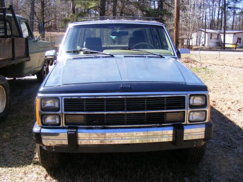 Jeep Cherokee front view, light blue with black hood, chrome bumper, parked outdoors