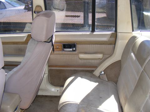 Interior of a Jeep Cherokee with tan seats and door panels. A metal cage is visible through the window