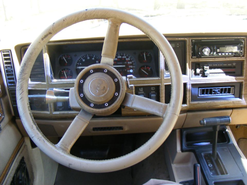 Tan Jeep Cherokee interior with a worn steering wheel and dashboard