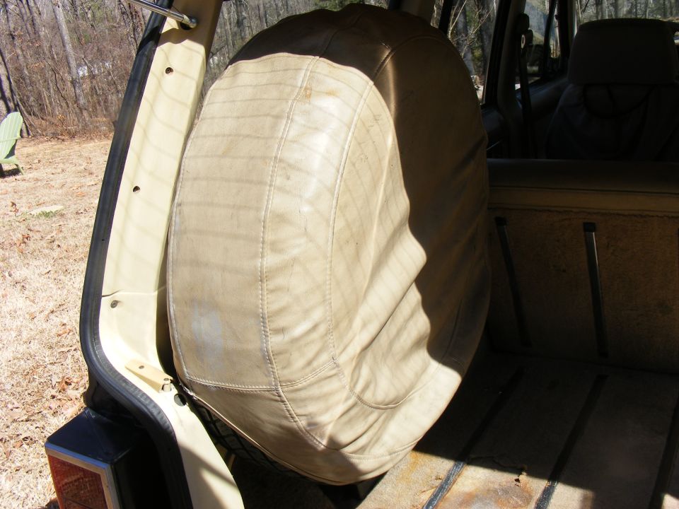 Tan vinyl spare tire cover inside the cargo area of an older SUV