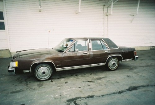 Brown four-door full-size sedan in side profile with wire wheel covers