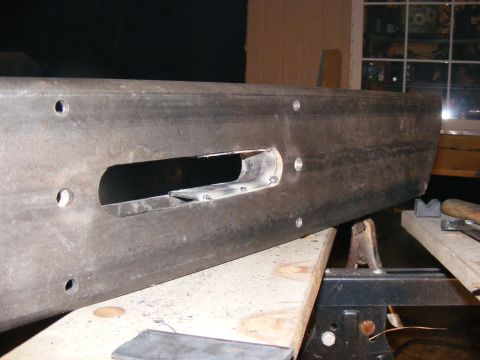 Close-up of a metal bumper being modified with a rectangular cutout