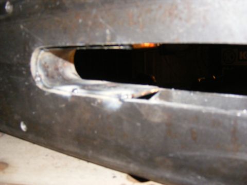 Close-up of a metal part with a cut-out and visible welds