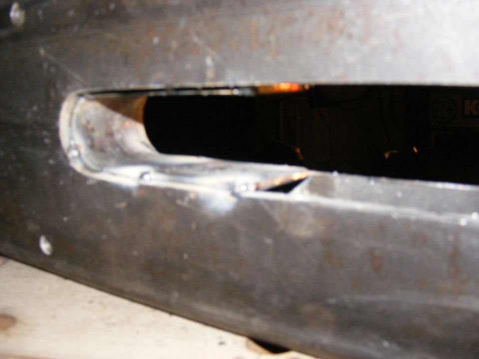 Close-up of a metal part with a cut-out and visible welds