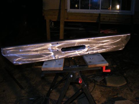 Custom metal bumper with winch cutout, resting on sawhorses