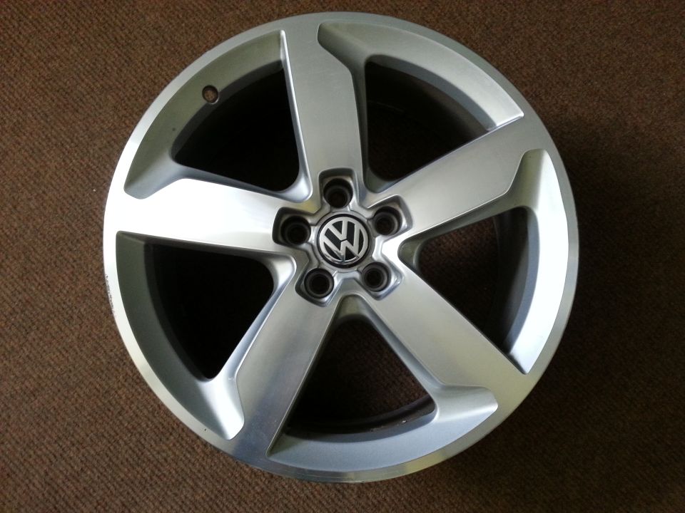 Silver Volkswagen wheel with five spokes and a central VW logo