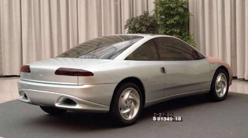 Silver concept car with tinted windows and a rounded rear. Unfinished front fender
