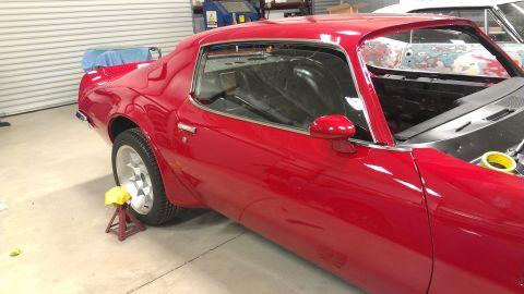 1972 Pontiac Trans Am - A red Pontiac Firebird is seen in a garage with its hood open, possibly undergoing restoration.
