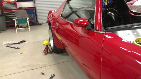 1972 Pontiac Trans Am - Side view of a red 1972 Pontiac Trans Am in a garage, supported by a jack stand.