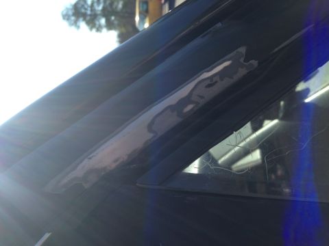 1990 Ford Bronco - Close-up of damaged car window trim and scratched glass.