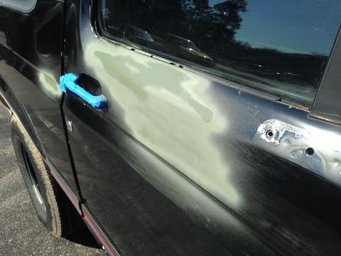 1990 Ford Bronco - Body filler is applied to the driver's side door of a 1990 Ford Bronco.