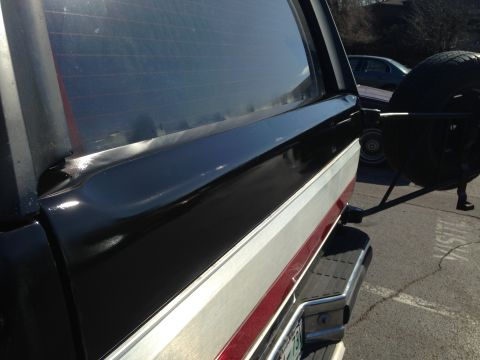 1990 Ford Bronco - Rear view of a black and silver Ford Bronco, showing its spare tire mount and chrome bumper.