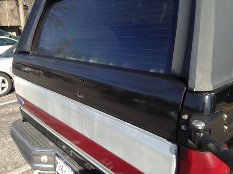 1990 Ford Bronco - Rear view of a two-tone SUV, a black top and silver lower body with a red accent stripe.