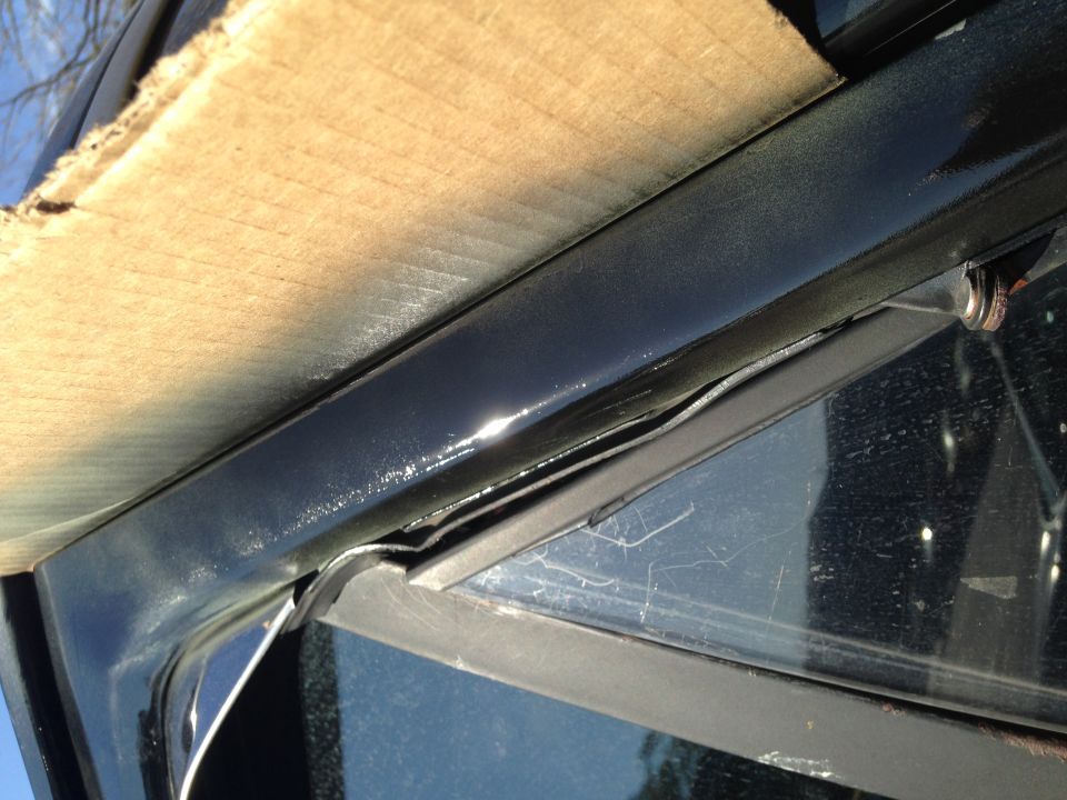 Close-up of car door frame with wood paneling attached, showing weather stripping and a reflection in the glass