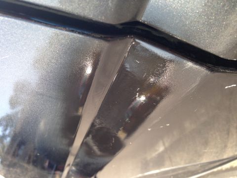 1990 Ford Bronco - Close-up view of a car's body panel seam, showing metallic gray paint and black trim.