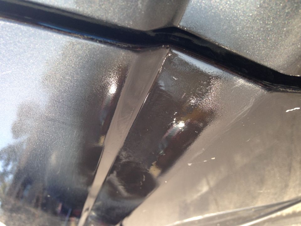 Gray metallic car body panel seam with black trim and visible scratches