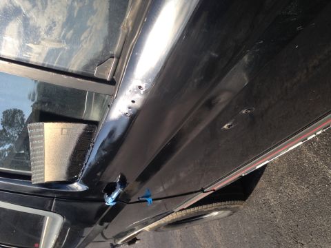 1990 Ford Bronco - Detail of a vehicle's side panel, showing holes and tape, likely during repair or modification.