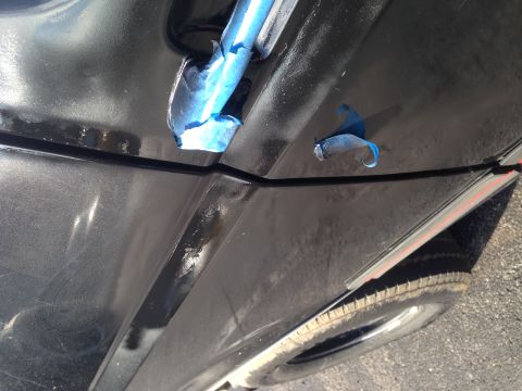 1990 Ford Bronco - Detail of a car's bodywork, showing a seam and masking tape, with a tire in the background.