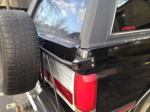 1990 Ford Bronco - Rear view of a 1990 Ford Bronco showing its external spare tire mount and a humorous sticker.