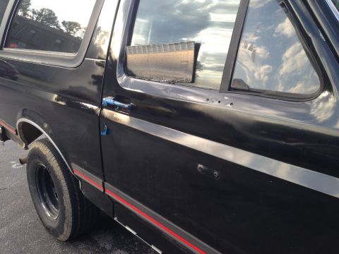 1990 Ford Bronco - Side view of a black SUV, showing the door, wheel, and trim details.