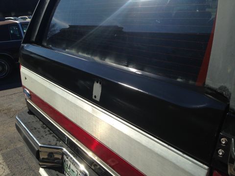 1990 Ford Bronco - Close-up of the rear of a two-tone Ford Bronco, showing the side panel and bumper detail.