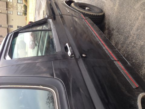 1990 Ford Bronco - Side view of a black SUV, showing its door handle and a red stripe along the body panel.