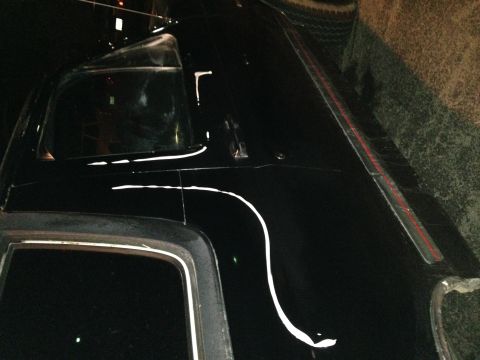 1990 Ford Bronco - A black SUV is partially visible with white pinstriping on its body.