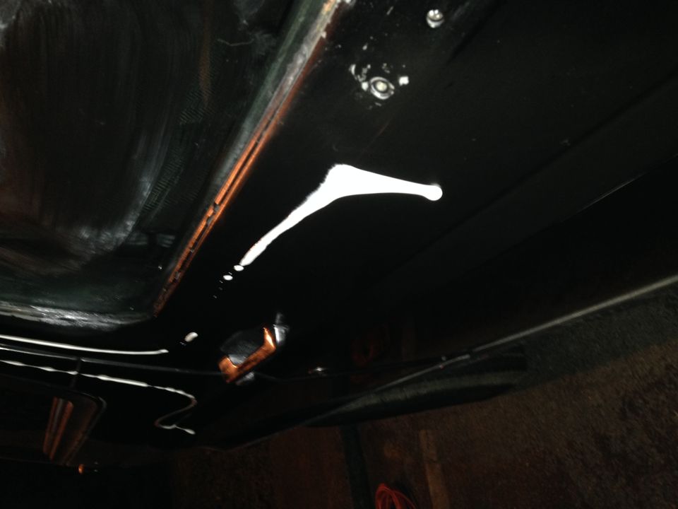 Underside of vehicle with white paint drips on black undercoating