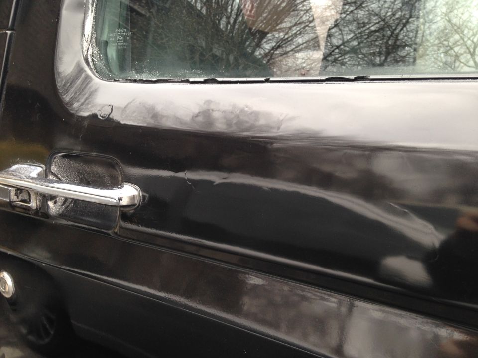 Black 1990 Ford Bronco door with chrome handle and peeling paint on trim