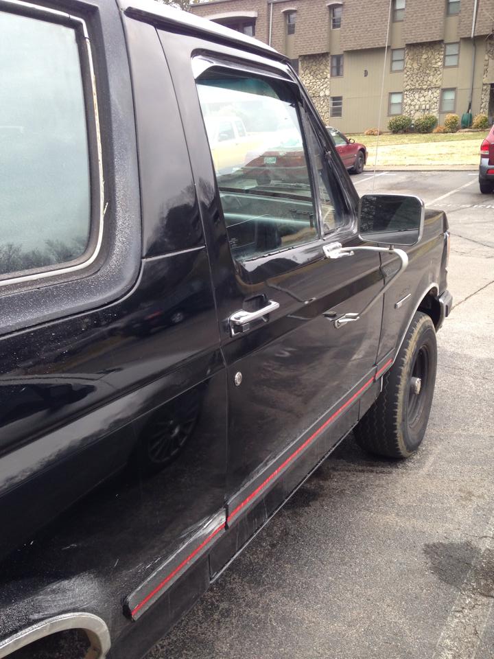 Black 1990 Ford Bronco side view, showing door handle, side trim, and rear wheel