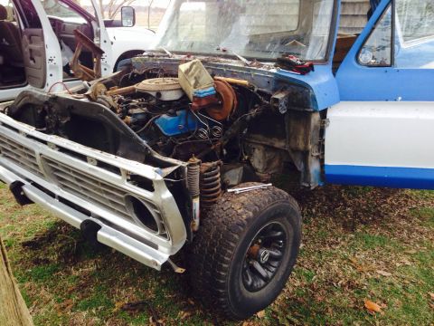 1979 Ford Bronco - This blue and white pickup truck shows its exposed engine and front end, with a white truck visible behind it.