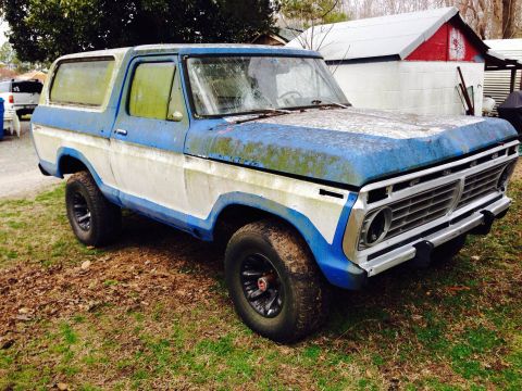1979 Ford Bronco - This weathered 1978 Ford Bronco sits in a grassy yard, its paint faded and showing signs of age.