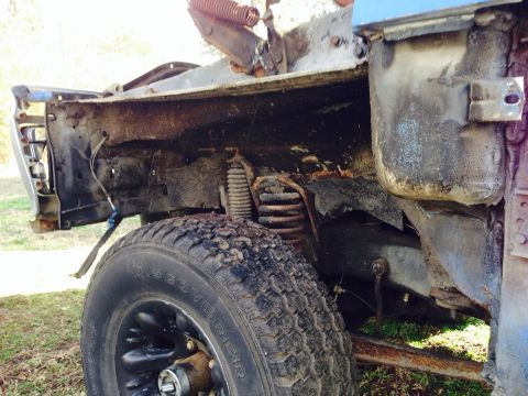 1979 Ford Bronco - The vehicle's front suspension and chassis are heavily rusted, indicating extensive damage and neglect.