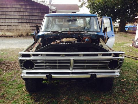 1979 Ford Bronco - This 1975 Ford pickup truck is shown from the front with its hood open, revealing the engine bay and a prominent grille.