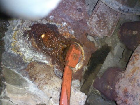 1998 Ford Crown Victoria - A close-up view of a corroded engine block heater plug, with an orange tool inserted.