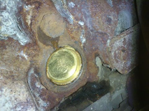 1998 Ford Crown Victoria - A brass cylinder block heater is visible on a heavily corroded engine part.