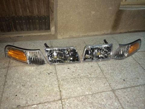 1998 Ford Crown Victoria - A set of four car headlights and amber corner lights are displayed on a tiled surface.